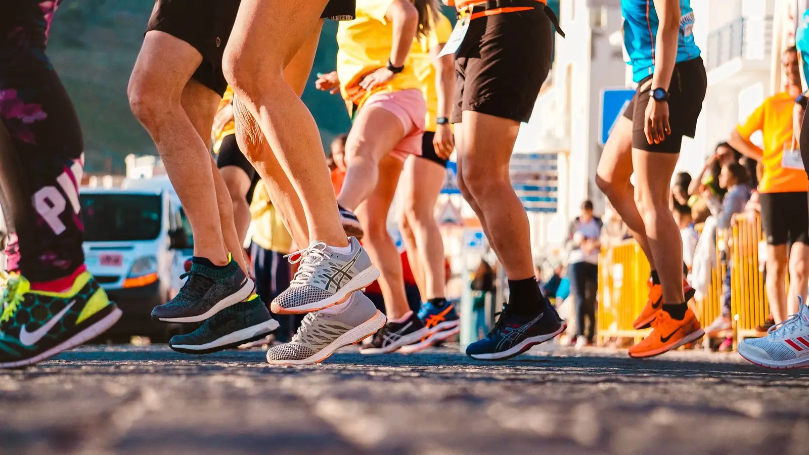 Runners’ legs and shoes at the start of a race in warm morning light.