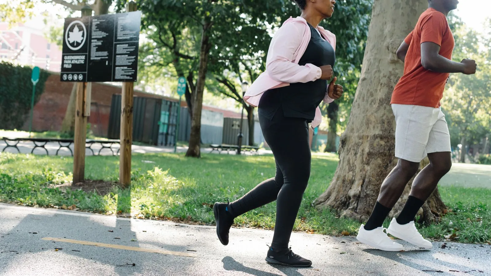 Two people jogging side by side along a park path at an easy, conversational pace.
